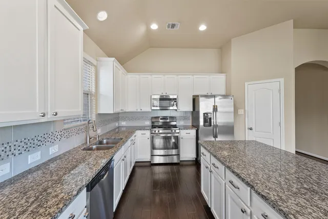 a kitchen with stainless steel appliances granite countertop a sink refrigerator and microwave
