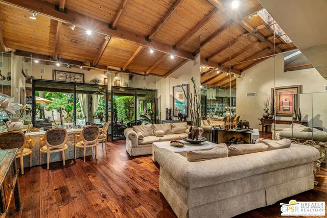 a dining hall with stainless steel appliances granite countertop a stove a sink a dining table and chairs with wooden floor