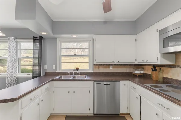 a kitchen with granite countertop a sink white cabinets and a window