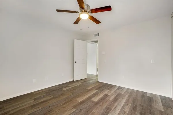 an empty room with wooden floor ceiling fan and ceiling fan