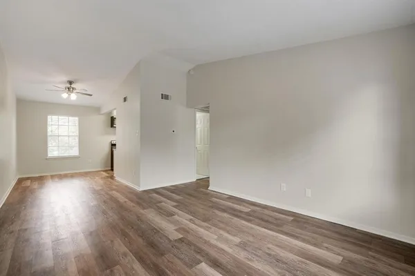 a view of an empty room with wooden floor and a window