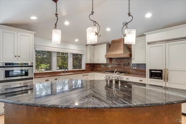 a view of a kitchen with granite countertop center island wooden floor stainless steel appliances and a window