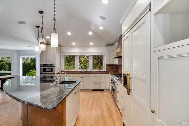 a kitchen with granite countertop a sink stainless steel appliances and window
