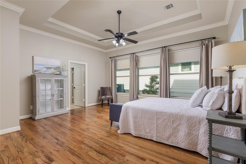 2205 State Boulevard McKinney, TX 75071 - Photo 15 of 40 Primary bedroom featuring a tray ceiling, newly installed wood floors, a ceiling fan, and ornamental molding.