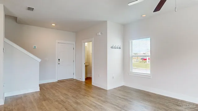 a view of an empty room with wooden floor and a window