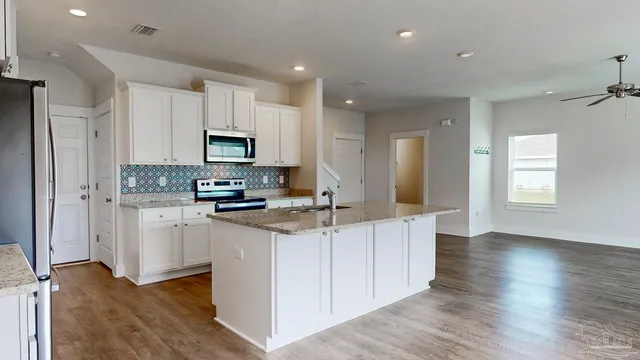 a kitchen with granite countertop a refrigerator and a stove top oven