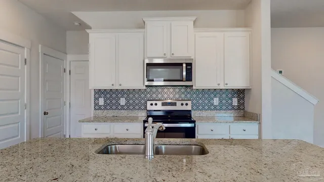 a kitchen with granite countertop a stove a microwave and a sink
