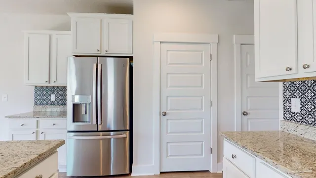 a kitchen with stainless steel appliances granite countertop white cabinets and refrigerator