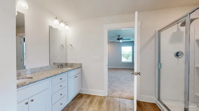 a bathroom with a granite countertop sink two mirror and shower