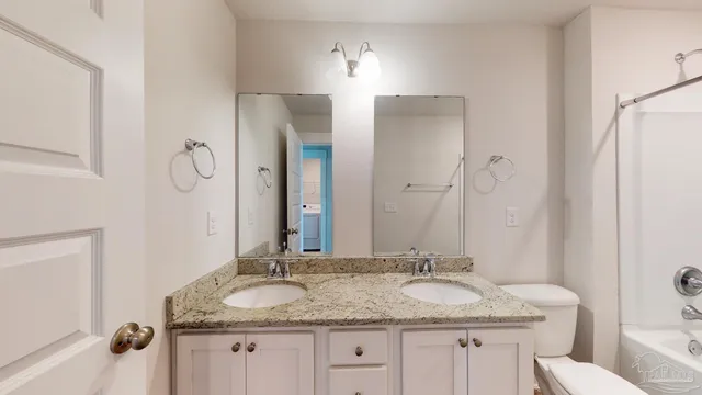 a bathroom with a granite countertop tub sink toilet and a mirror