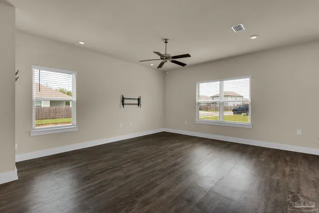 an empty room with wooden floor chandelier fan and windows
