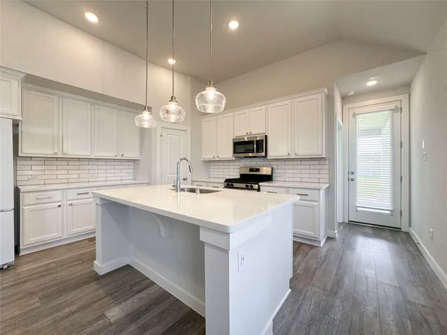 a kitchen with kitchen island granite countertop a sink cabinets and wooden floor