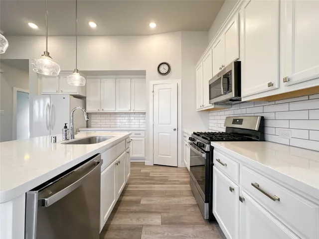 a kitchen with stainless steel appliances granite countertop a sink a stove and a refrigerator