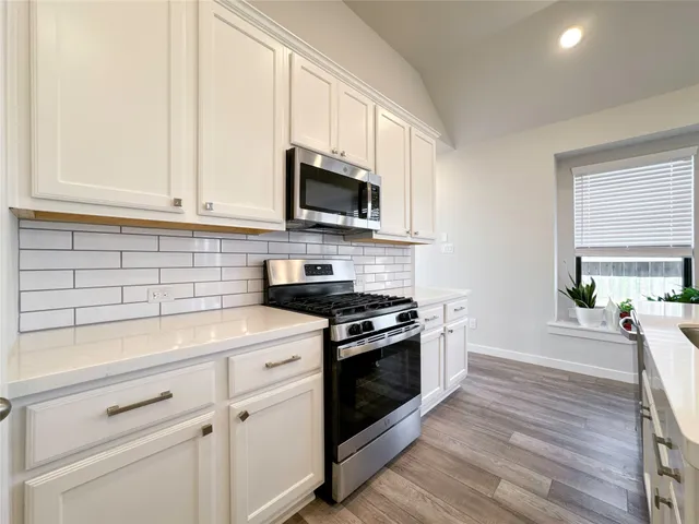 a kitchen with white cabinets and appliances
