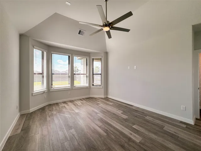 a view of an empty room with a window and wooden floor