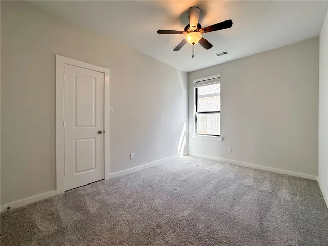 an empty room with windows and fan