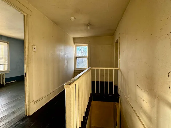 a view of a hallway with wooden floor and staircase
