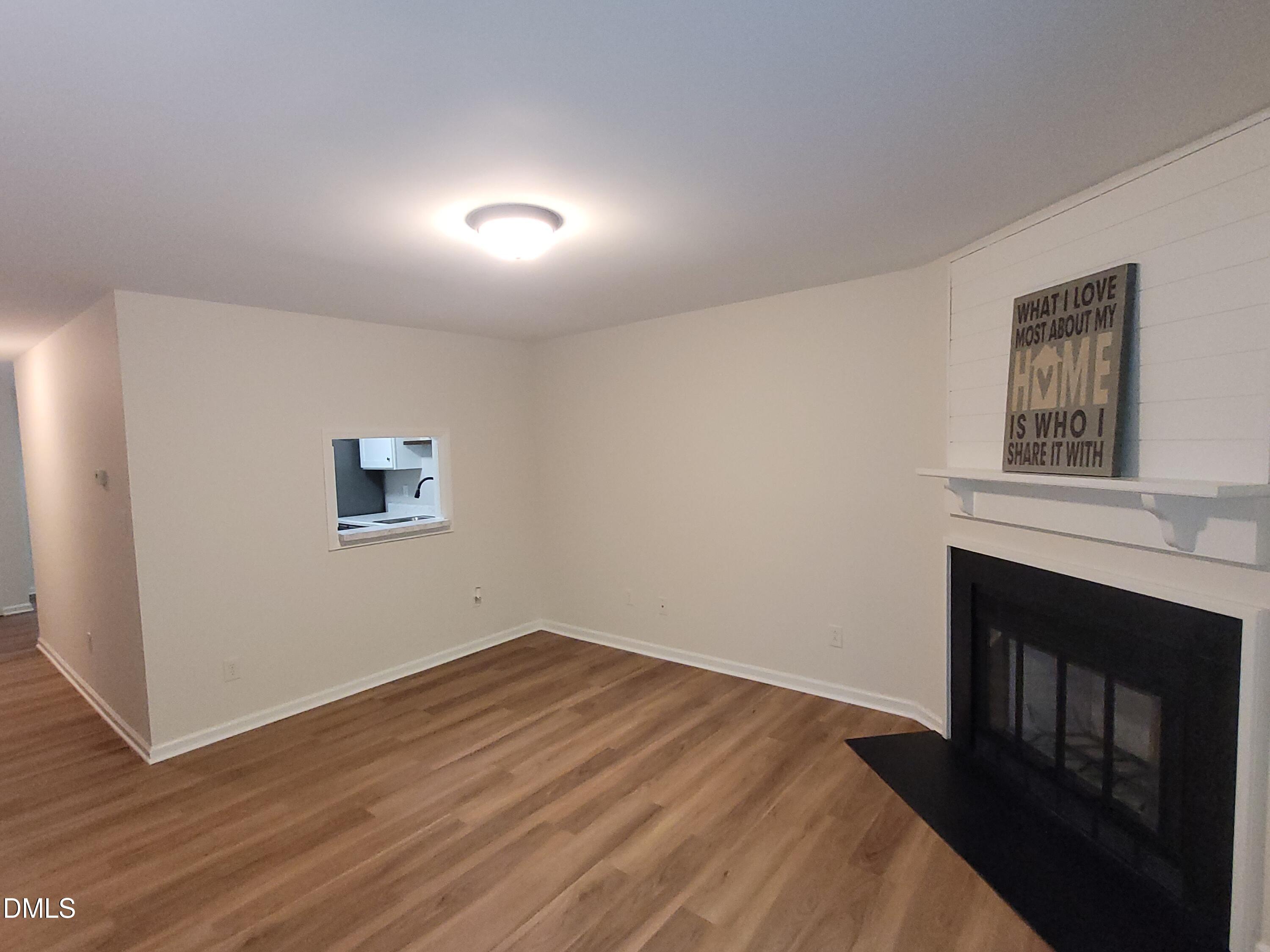 4651 Timbermill Court, Unit 103 Raleigh, NC 27612 - Photo 6 of 40 Wood-finish flooring, recessed pass-through window, fireplace with black surround, white mantel, and ceiling-mounted light fixture