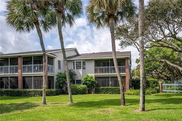 a view of a house with a yard and palm trees
