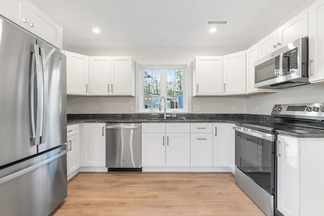 a kitchen with stainless steel appliances granite countertop a stove a sink and a refrigerator