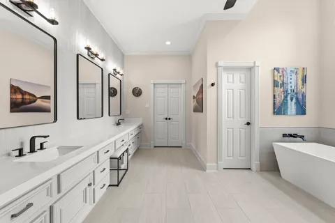 a bathroom with double vanity sinks a large mirror and a bathtub