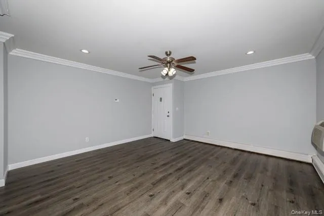 a view of an empty room with wooden floor and a ceiling fan