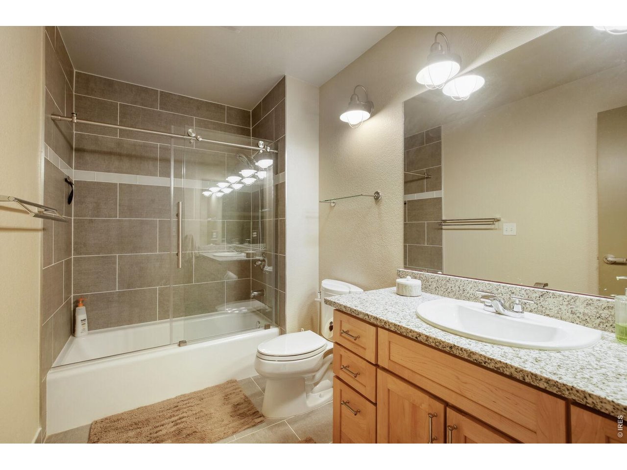 7550 Vardon Way Fort Collins, CO 80528 - Photo 22 of 29 a bathroom with a granite countertop sink a toilet a mirror and shower