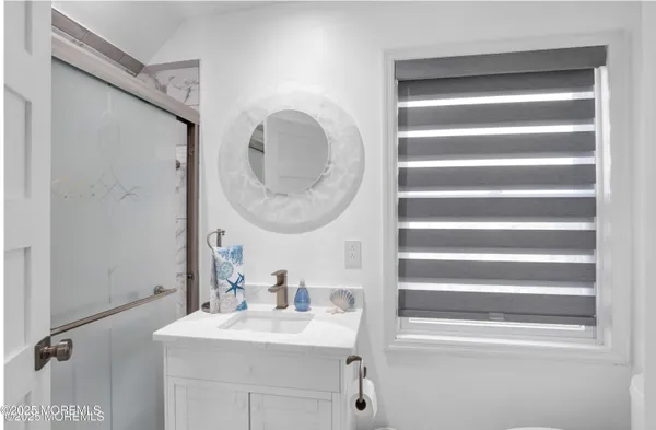 a bathroom with a sink a mirror a vanity and a shower