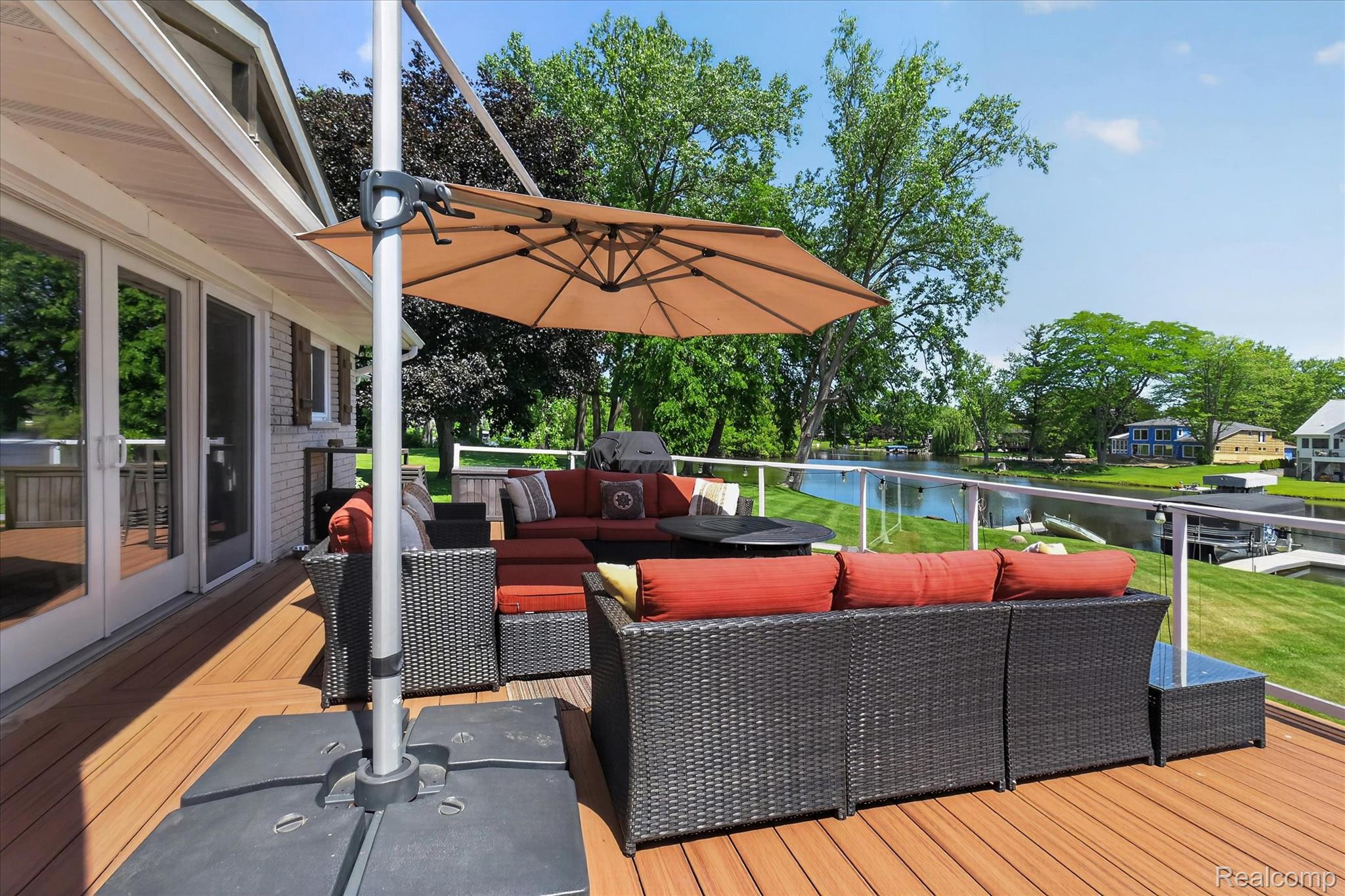 3860 East Commerce Road Commerce Township, MI 48382 - Photo 46 of 72 Expansive wood-finish deck with glass panel railing overlooking a body of water