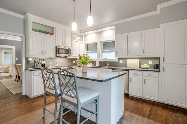 a kitchen with stainless steel appliances granite countertop a stove a sink a microwave a refrigerator and white cabinets