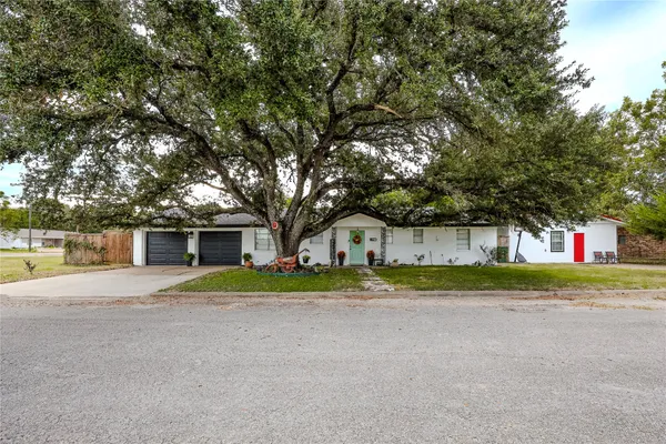 a front view of a house with a yard and trees