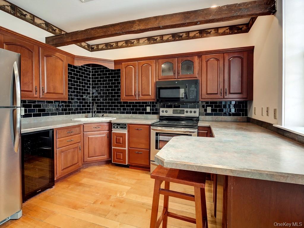 6 Bart Bull Road Middletown, NY 10941 - Photo 12 of 24 Kitchen featuring a breakfast bar, wine cooler, light countertops, appliances with stainless steel finishes, and brown cabinetry