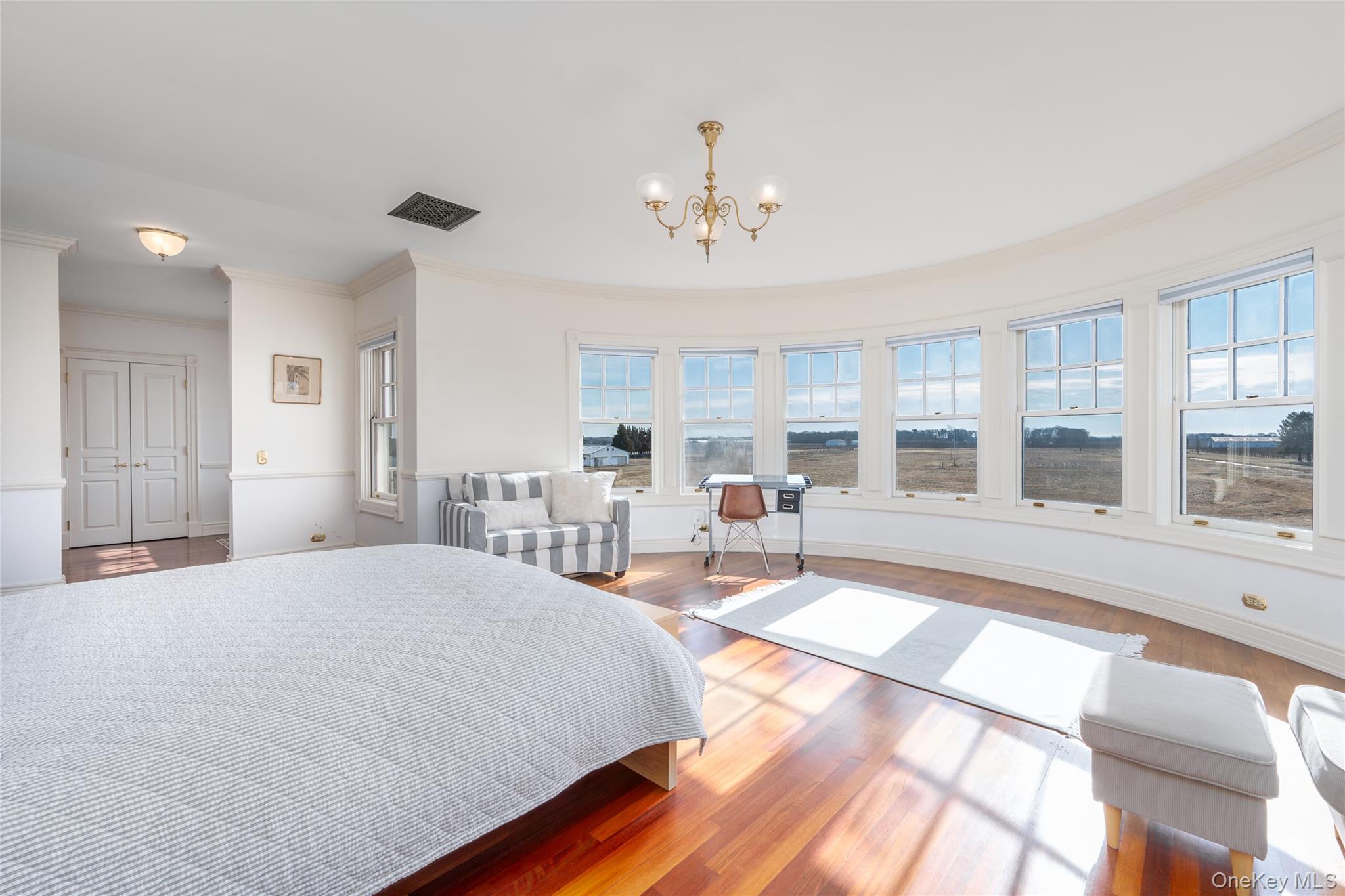 6133 Sound Avenue Riverhead, NY 11901 - Photo 24 of 42 a spacious bedroom with a large bed and a chandelier