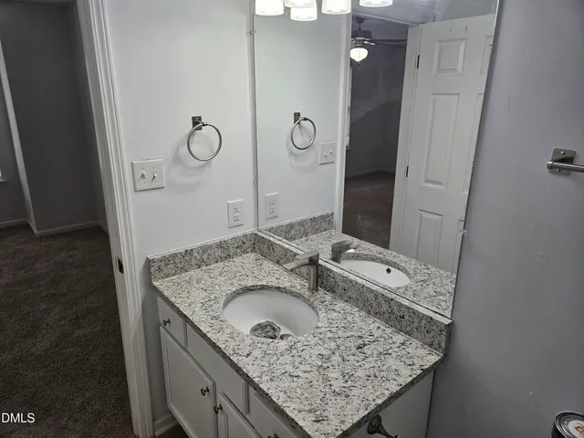 a bathroom with a granite countertop sink a mirror and shower