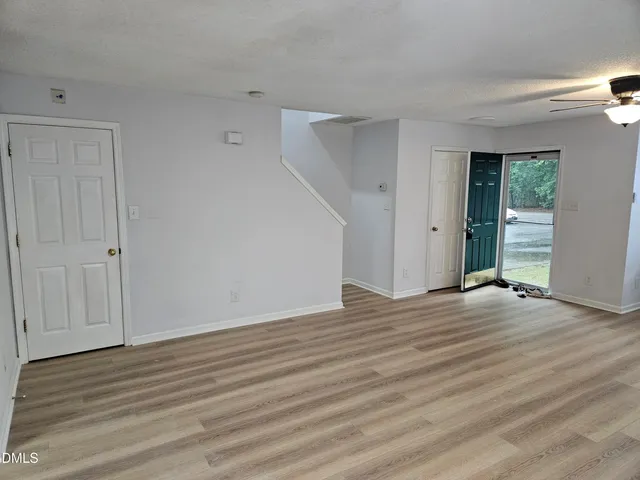a view of an empty room with wooden floor and closet