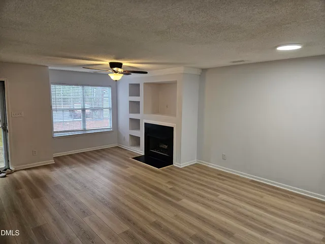 an empty room with windows fireplace and wooden floor