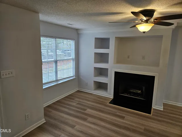 a view of an empty room with a fireplace and a window