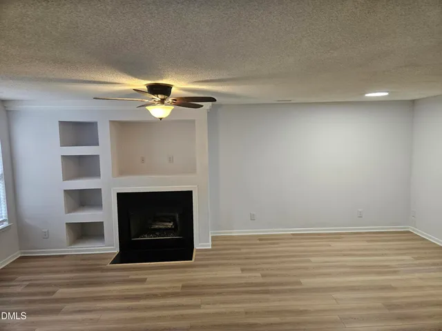 a view of a livingroom with wooden floor a fireplace and window
