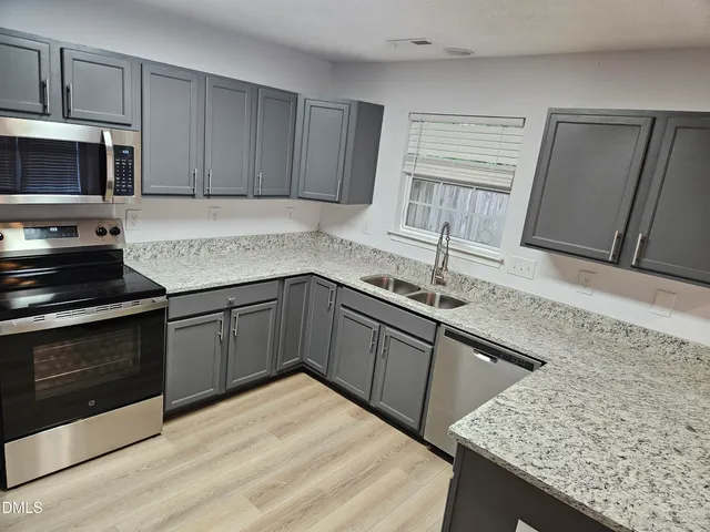 a kitchen with stainless steel appliances granite countertop a sink stove and microwave
