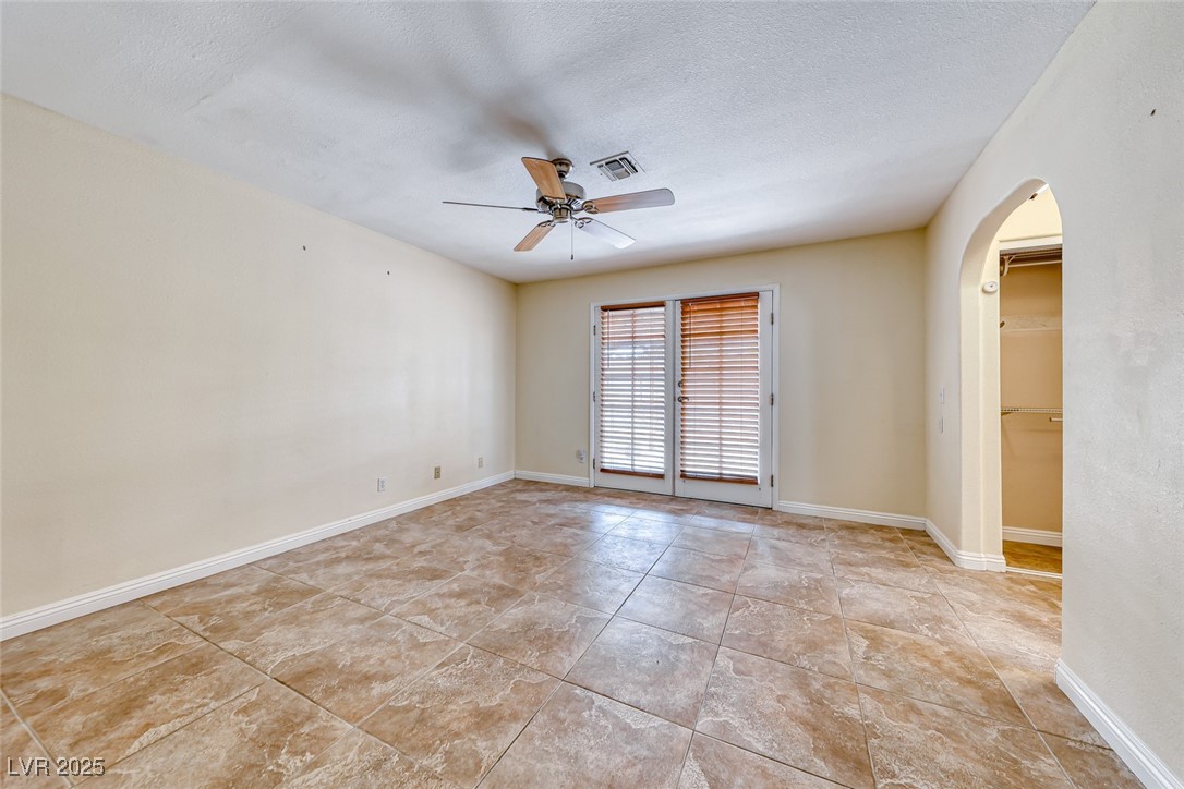 632 Arrayo Way Boulder City, NV 89005 - Photo 22 of 40 Unfurnished room featuring arched walkways, a ceiling fan, light tile patterned flooring, a textured ceiling, and baseboards