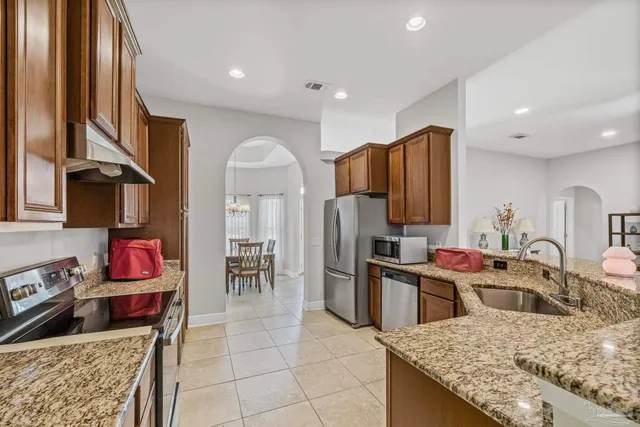 a kitchen with stainless steel appliances granite countertop a sink dishwasher stove refrigerator and cabinets