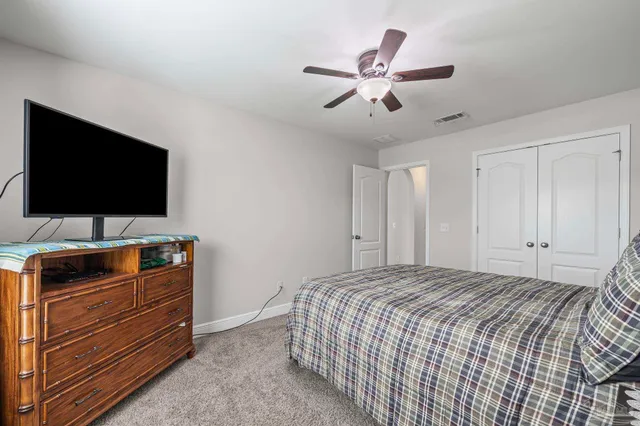 a bedroom with a bed and a flat tv screen on dresser