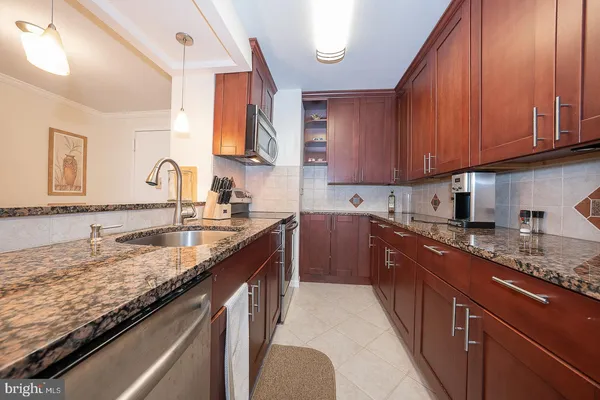 a kitchen with granite countertop stainless steel appliances a sink dishwasher stove and cabinets