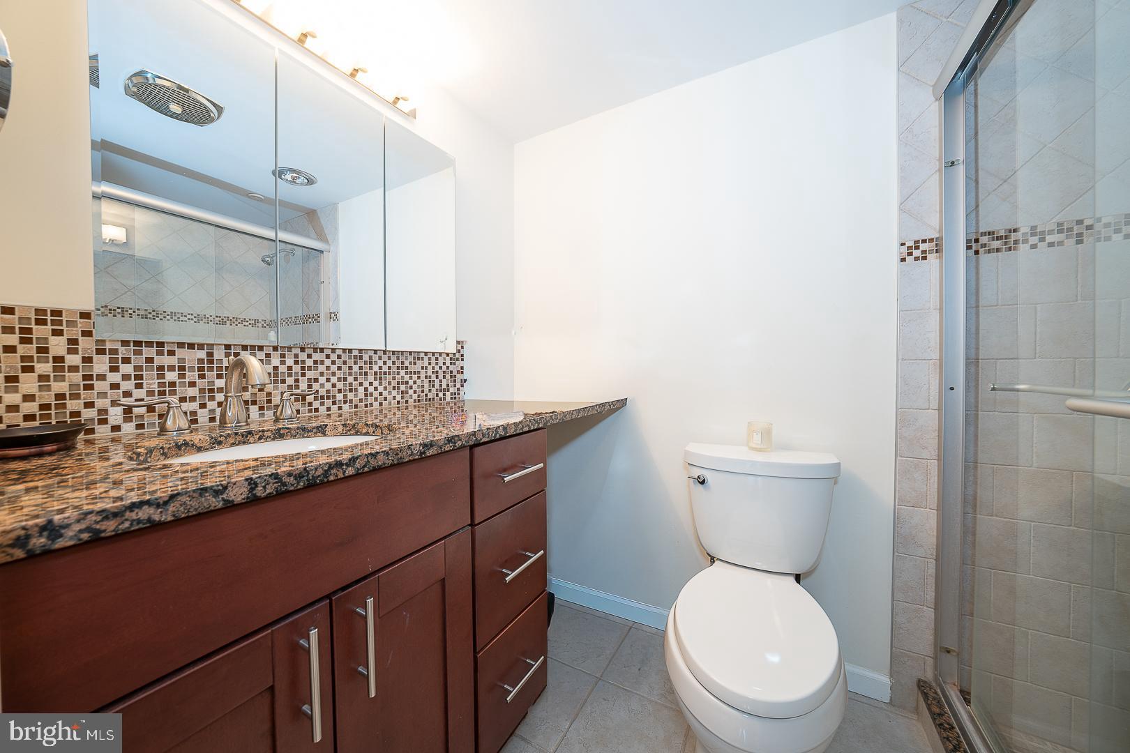 1919 Chestnut Street, Unit 2822 Philadelphia, PA 19103 - Photo 25 of 36 a bathroom with a granite countertop sink a toilet and a mirror