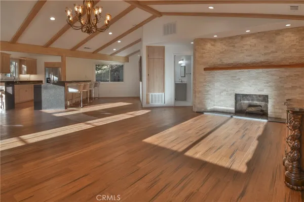 an open space with a fireplace a chandelier and wooden floor