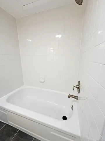 a bedroom with a bed lamp on desk and a window