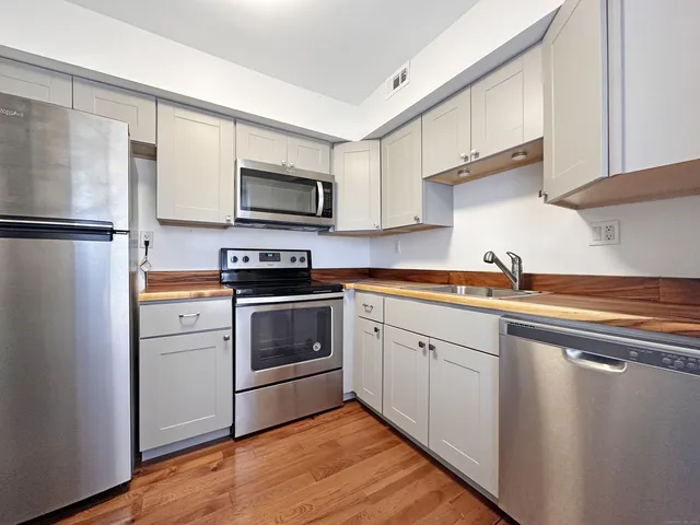 a kitchen with cabinets stainless steel appliances and a sink