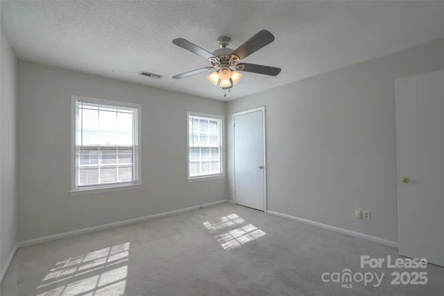 a view of an empty room with window and chandelier fan
