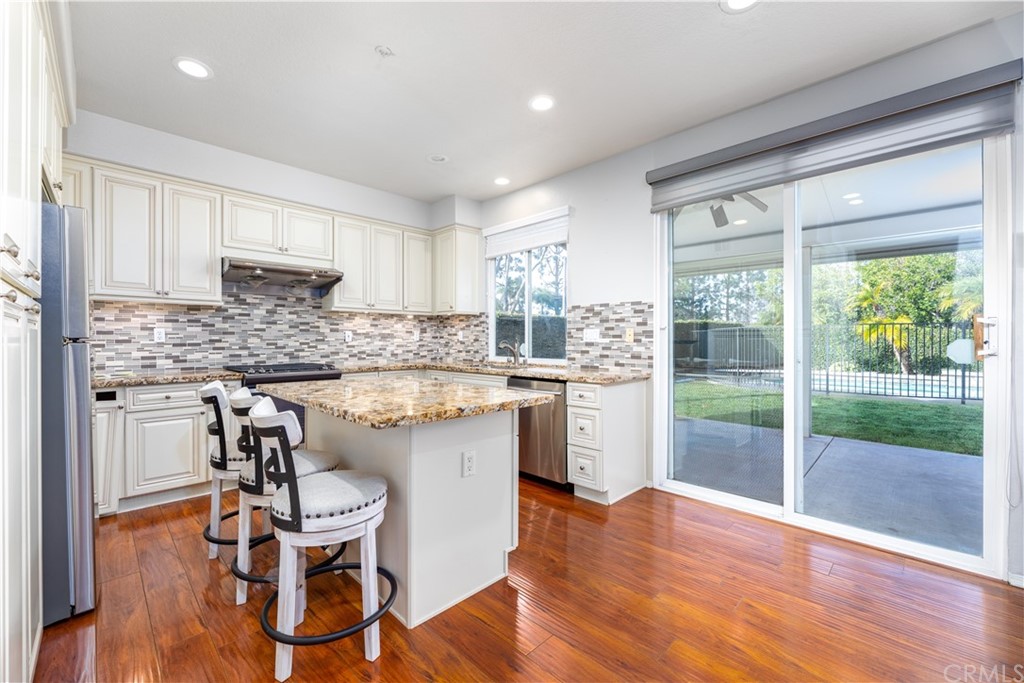 24 Silveroak Irvine, CA 92620 - Photo 7 of 23 a kitchen with granite countertop wooden floors white cabinets and stainless steel appliances