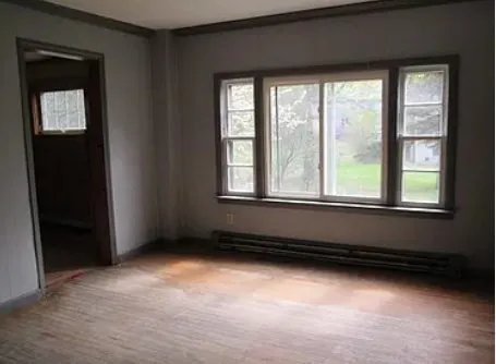 an empty room with wooden floor and windows